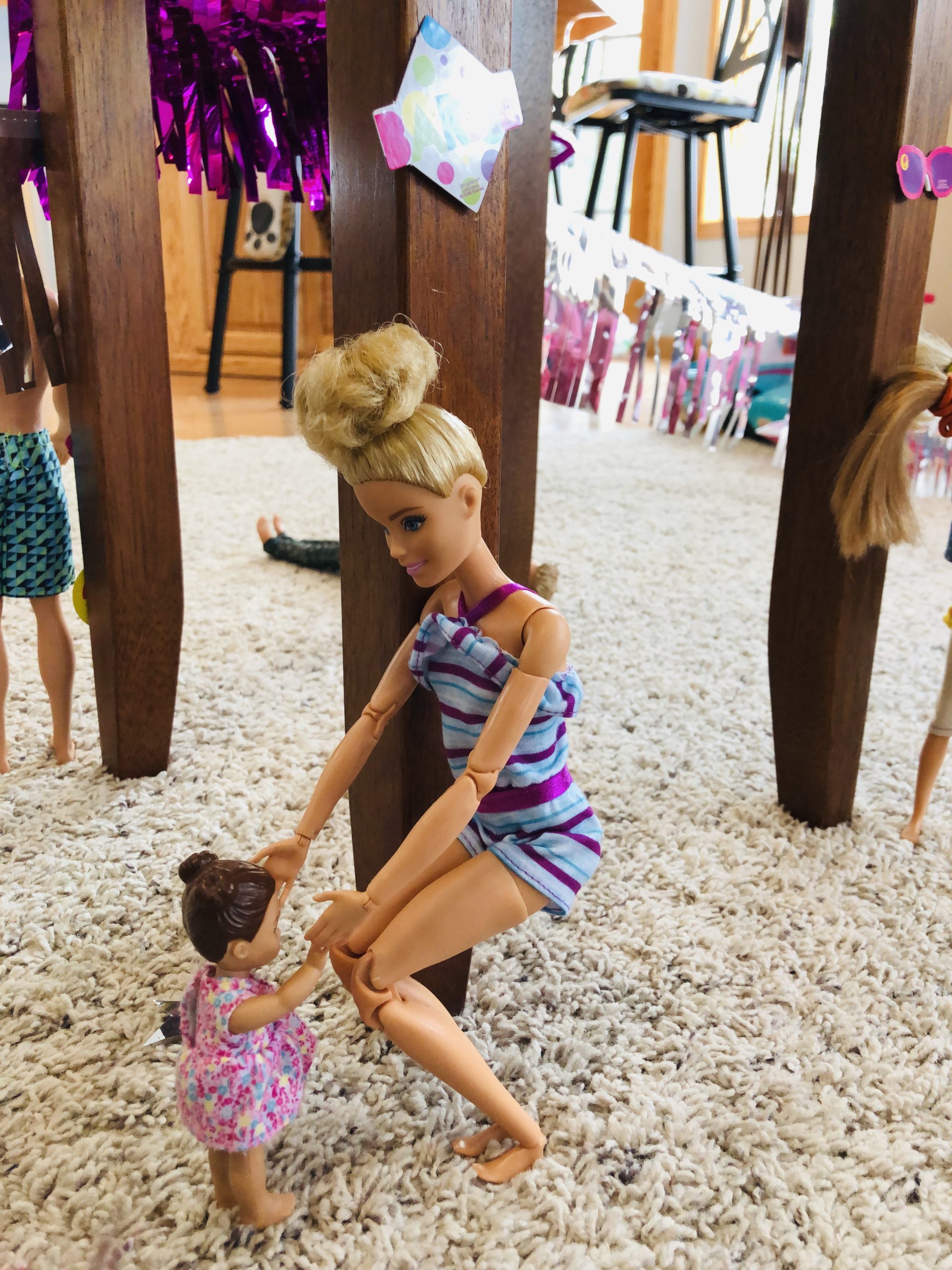 Barbie is holding hands and dancing with a smaller Barbie doll.