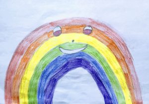 Colored pencil drawing of a rainbow with eyes, a nose and a smile. From The Rainbow in Winter, A Children's Story.