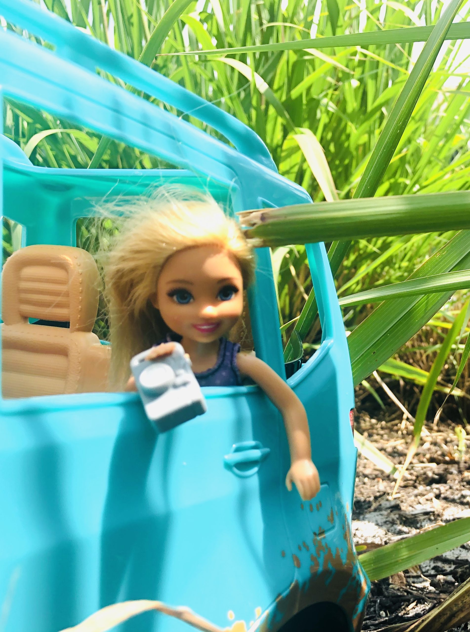 Chelsea doll hanging out the back window of the teal Barbie Jeep taking pictures of the scenery.