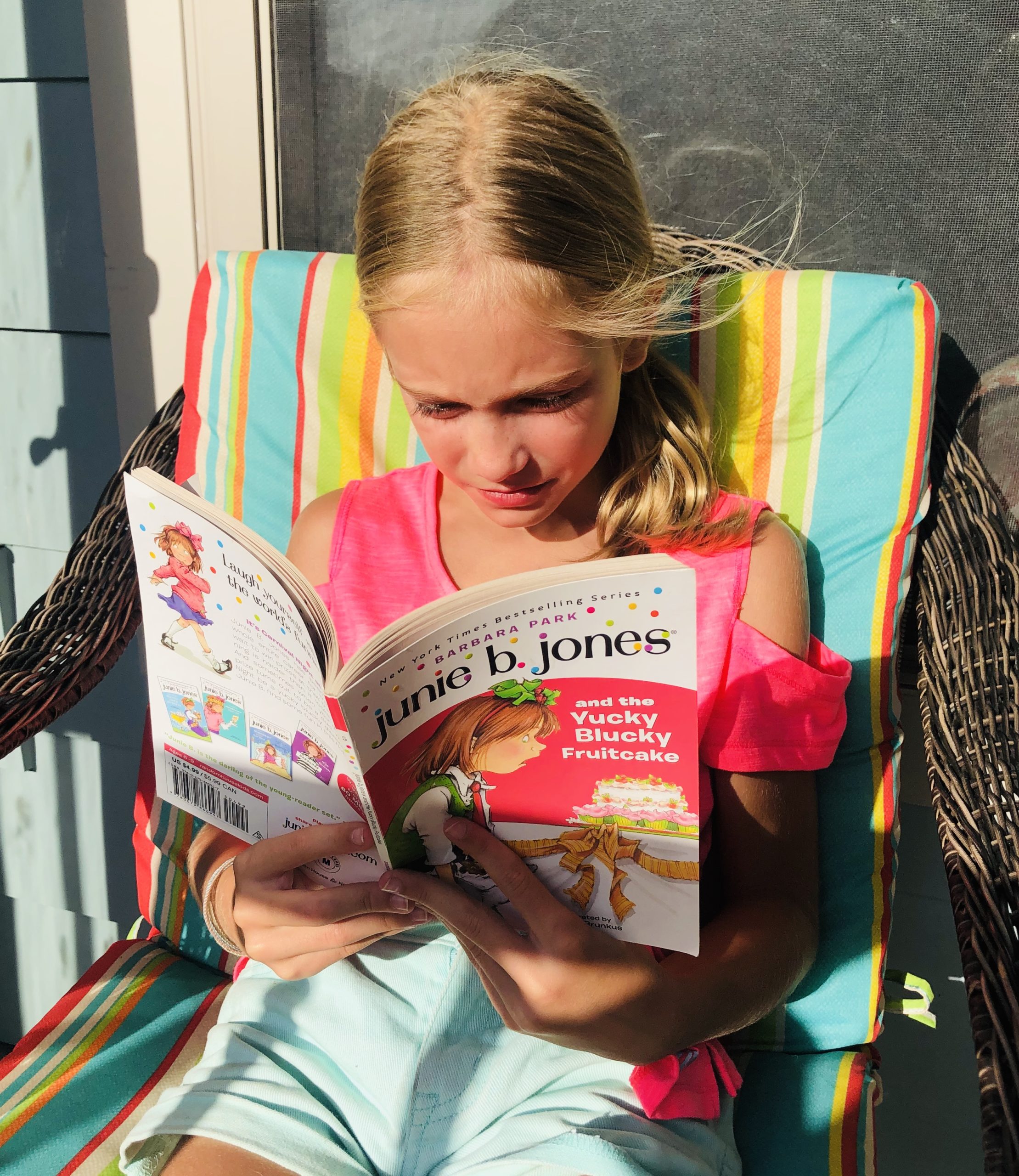 Blonde haired girl reading the book, Junie B. Jones and the Yucky Blucky Fruitcake for the children's book review.