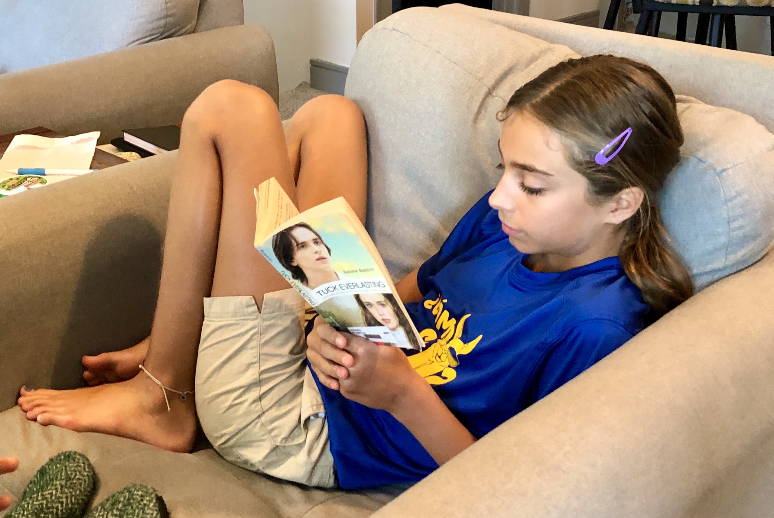 A young girl with her head down reading Tuck Everlasting by Natalie Babbitt for a children's Book Review by Kandblife.com