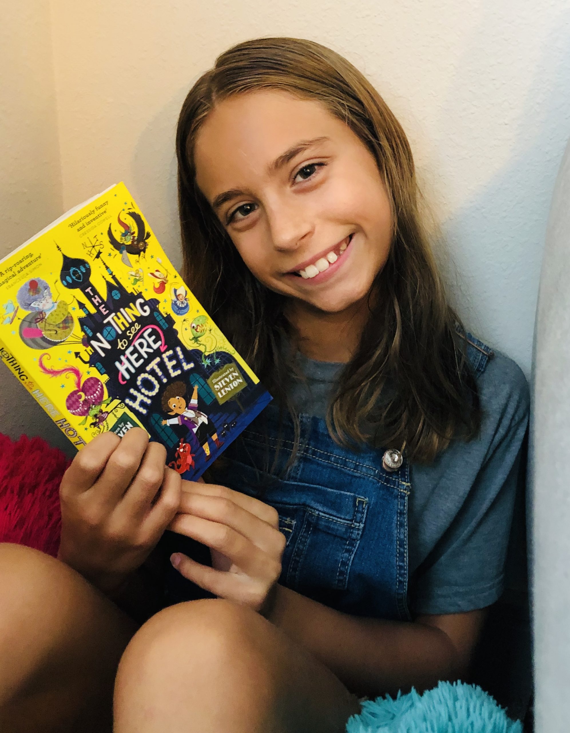 Kinley holding the book , The Nothing to see Here Hotel by Steven Butler for the the Children's Book Review.