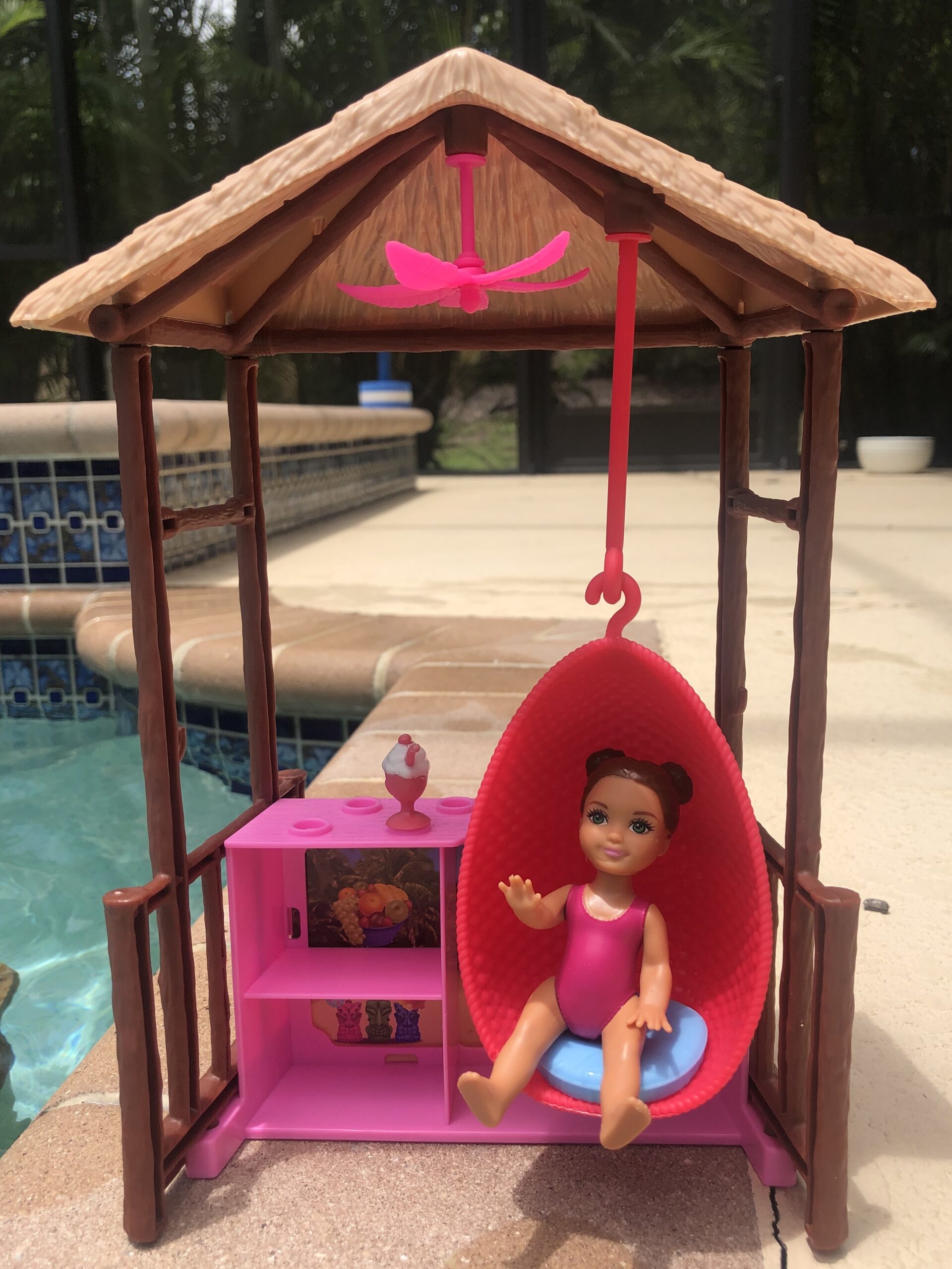 A baby Barbie Doll sitting in a swinging chair outside for the Barbie Doll Story.