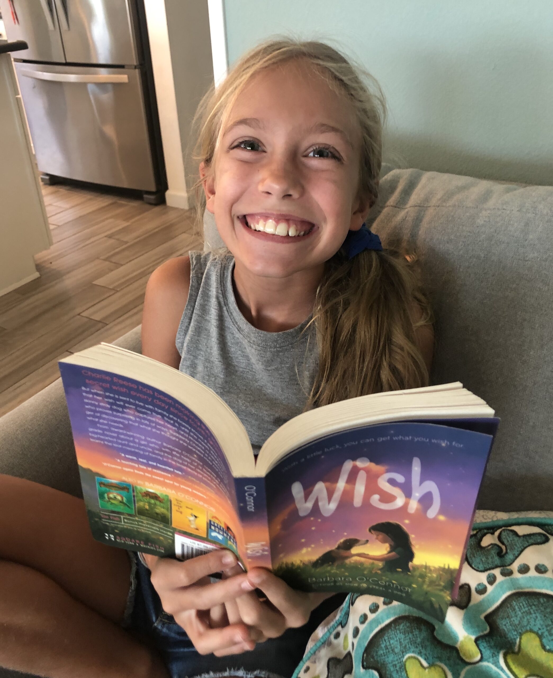 Blond haired girl reading Wish for the children's book review on it.