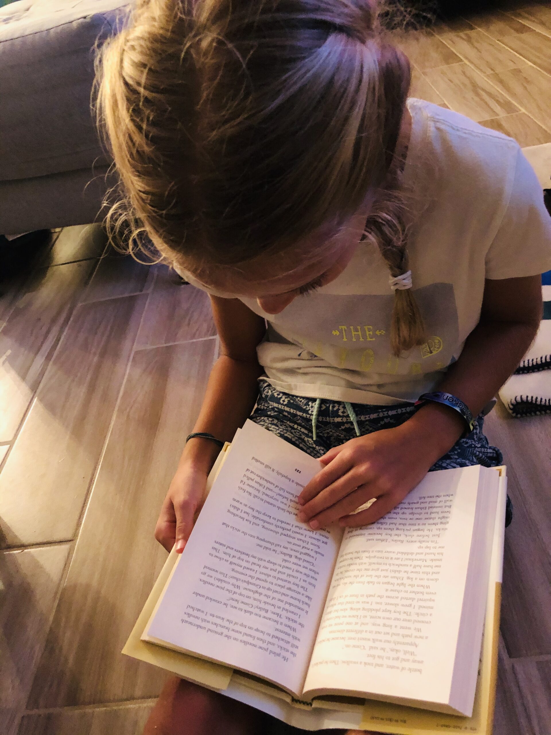 Blonde girl with braids reading a book. Book Review for Bailey's Story.