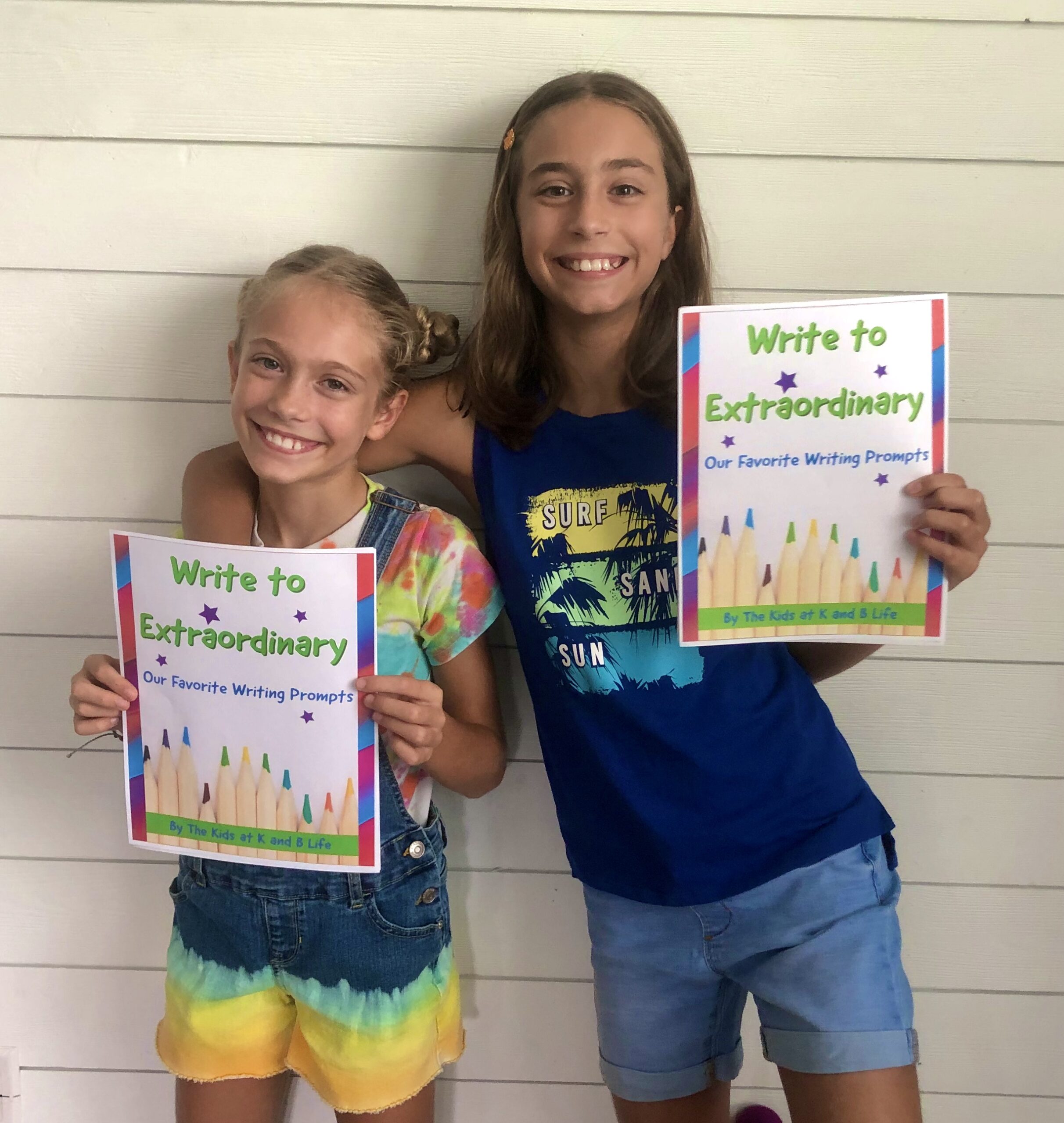 K and B holding up the Write to Extraordinary Guide for writing prompts and tips.