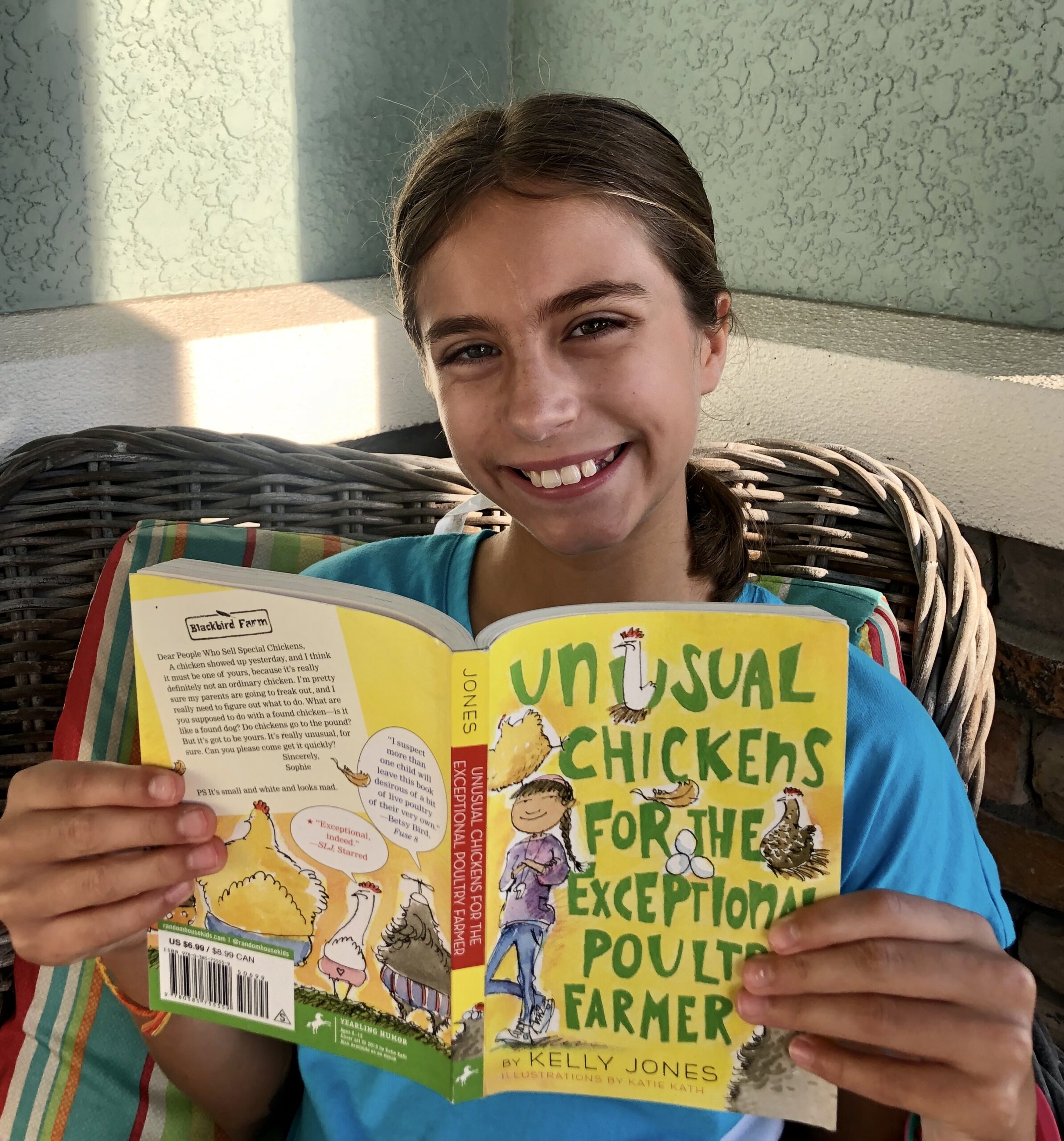 Girl smiling while reading Unusual chickens for the Exceptional Poultry Farmer for this book review.