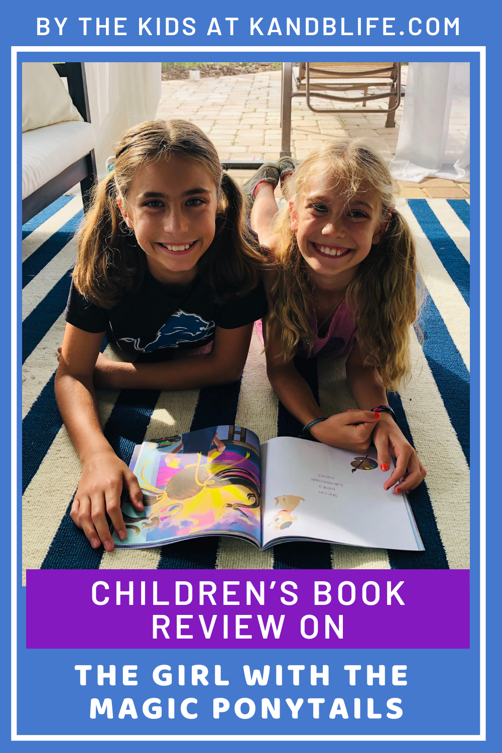 2 girls smiling at the camera, reading a book.