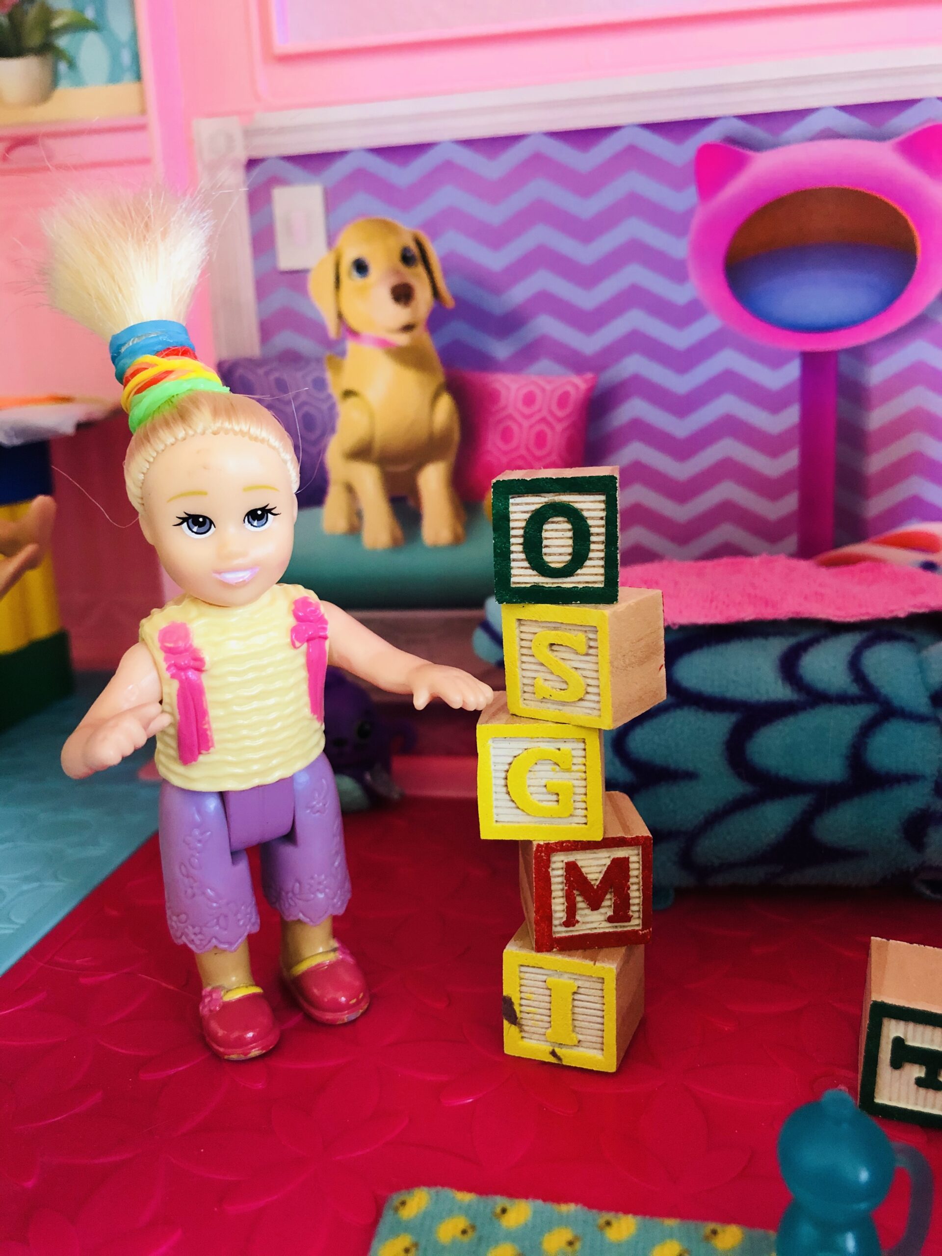 A little doll playing with blocks in the Barbie Dreamhouse.