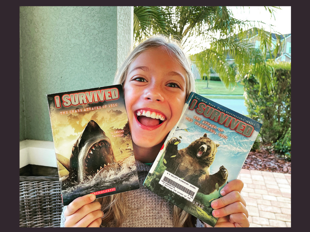 A young girl from K and B Life holding up her 2 favorite I Survived Books for the Book Review.